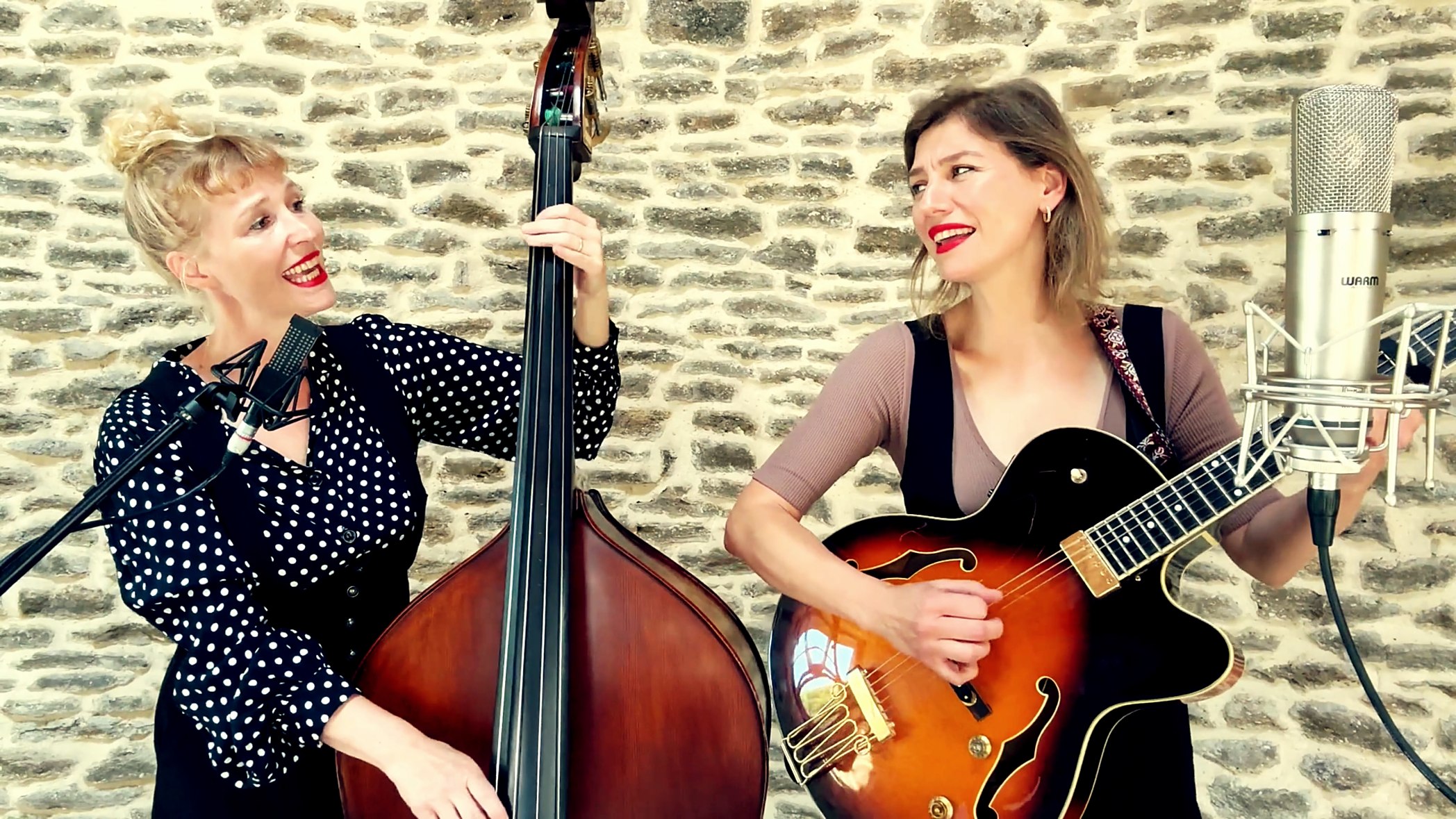 Rosanna Shura and Beth Packer of Hay Girl Hey singing to each other, one on double bass and one on guitar